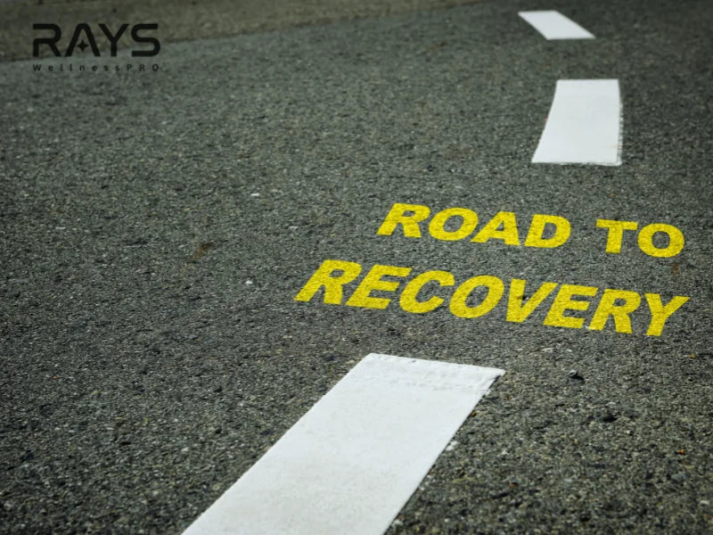 Yellow road to recovery sign painted on asphalt symbolizing health and wellness journey